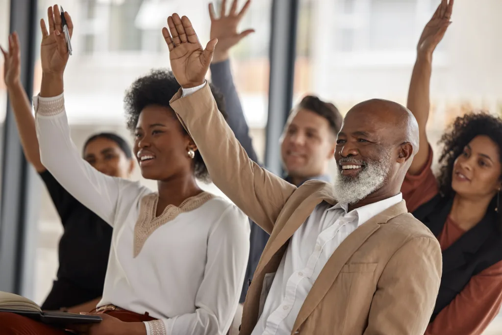 Group of people raising there hands to answer a question.
