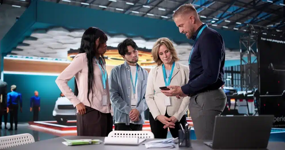 Four people looking at a phone at a marketing event.