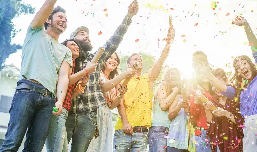 Group of people throwing up confetti at an outdoor event experience.