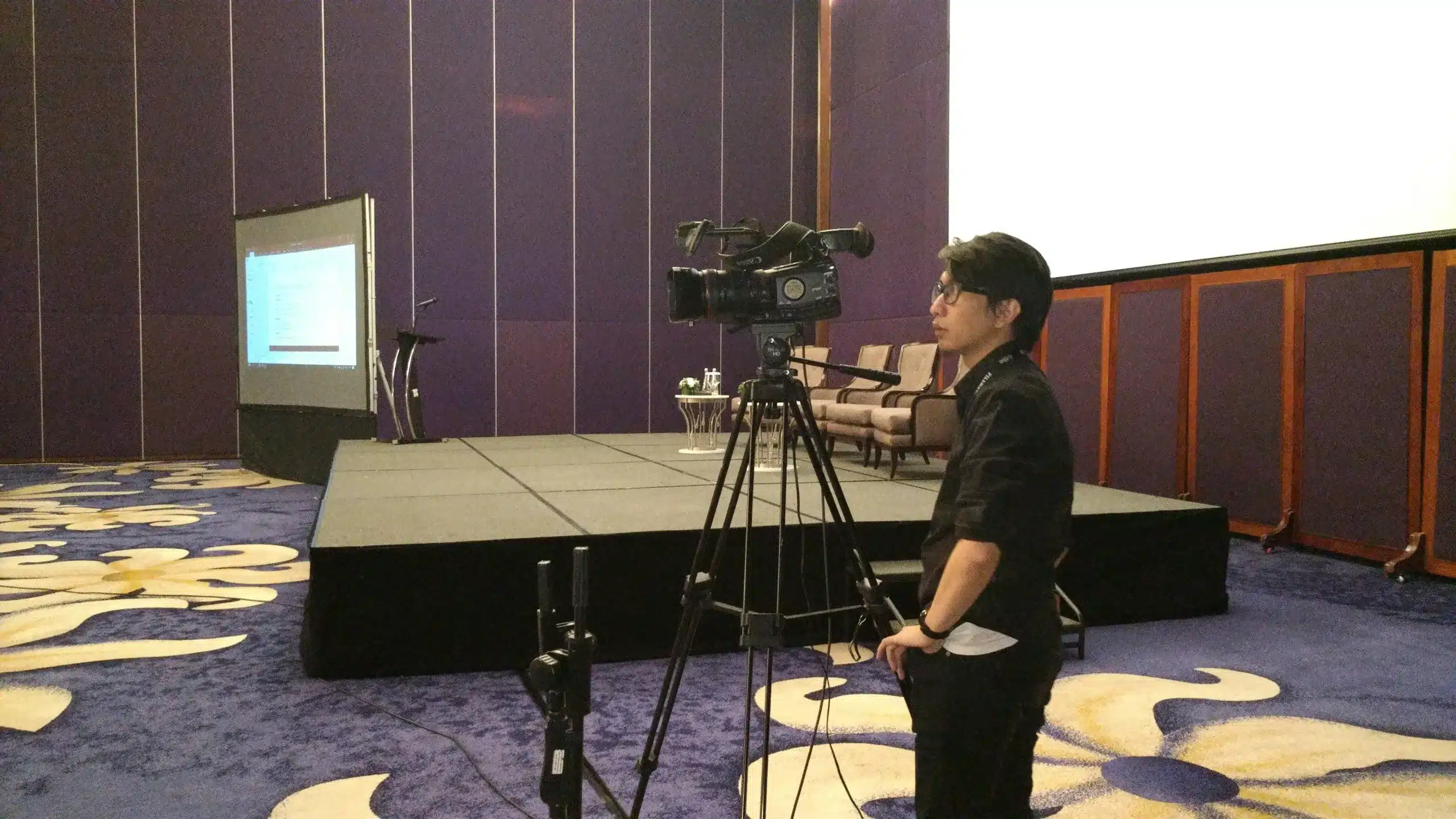 Cameraman operating professional video equipment at a hotel ballroom event